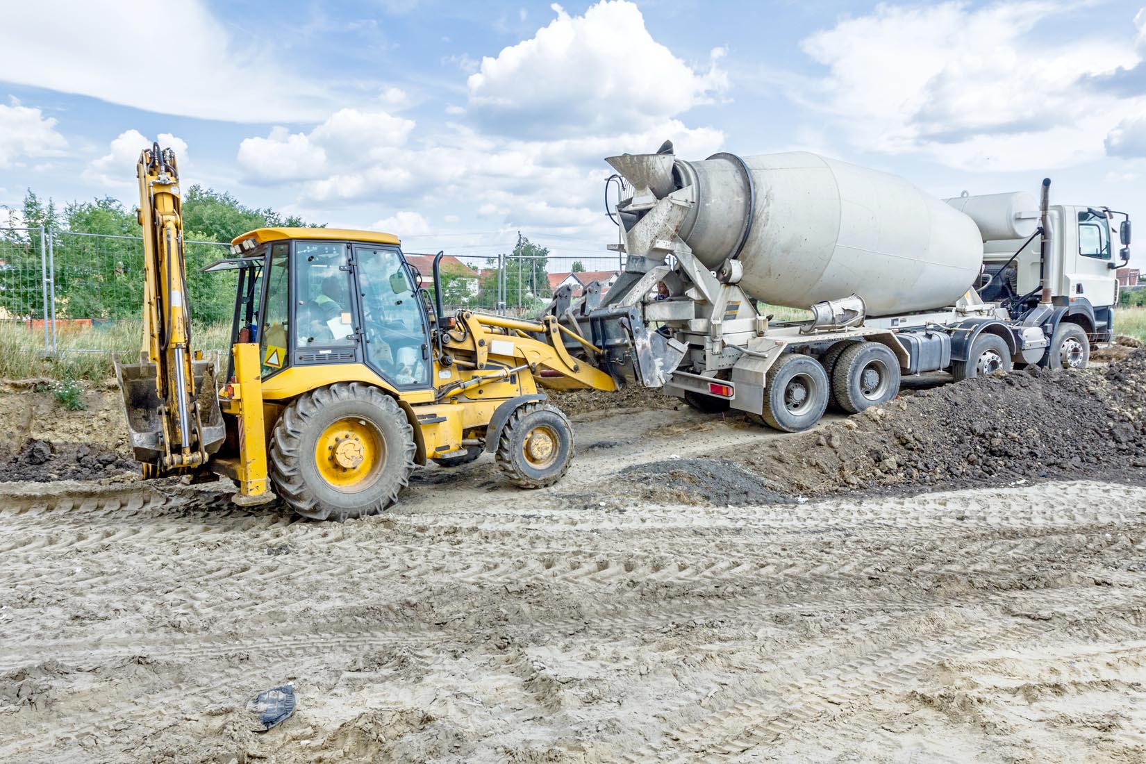 Truck Mixer In Process Of Pouring Concrete Into Bulldozer Scoop